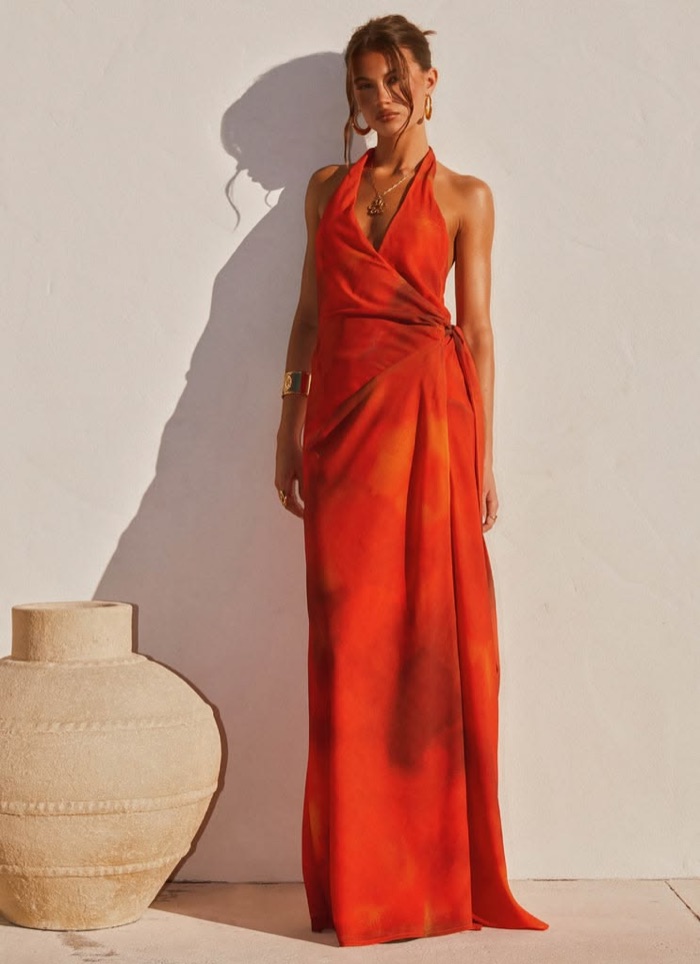 Woman in a fiery orange halter maxi dress with tie-dye print