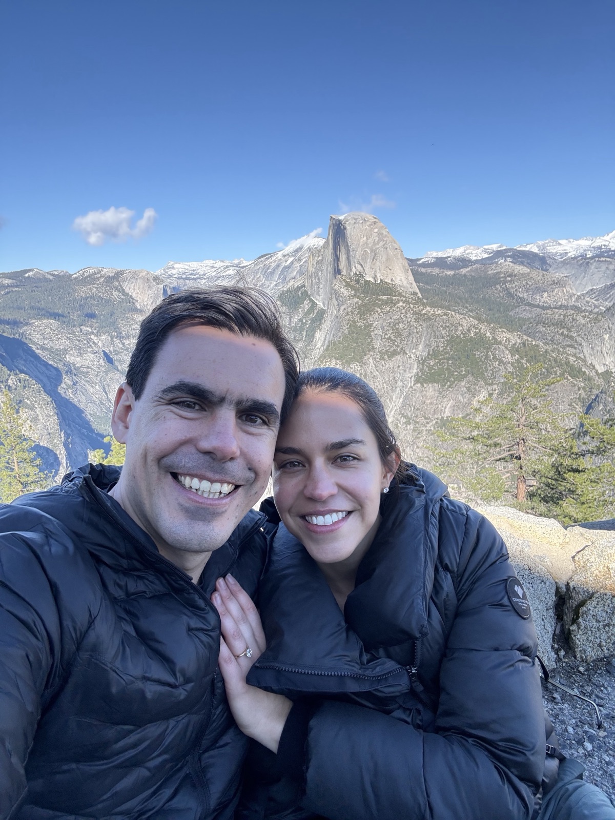 Paola and Andreas at their engagement in Yosemite, smiling together with Half Dome behind them.